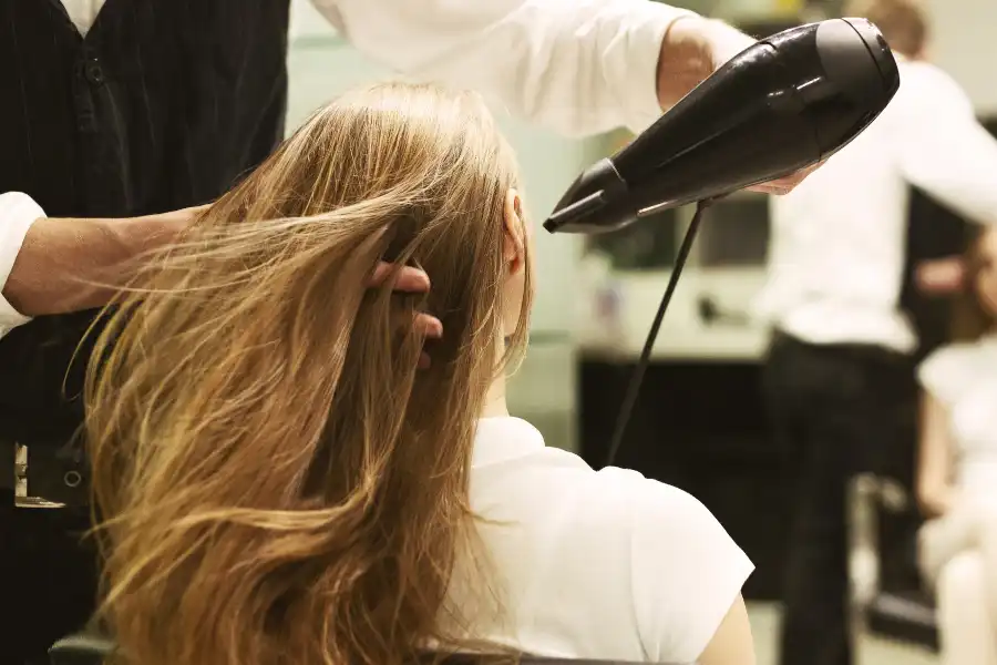 A woman with balayage hair being blow-dried